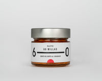 A glass jar with a metallic lid containing bonito tuna rillette, with a white label that reads '60 MILLAS' and has a red tomato symbol on it.